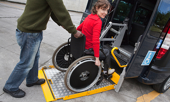 A wheelchair user being helped into an accessible transport vehicle