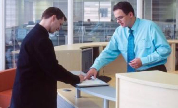 Image of a receptionist signing someone into a facility